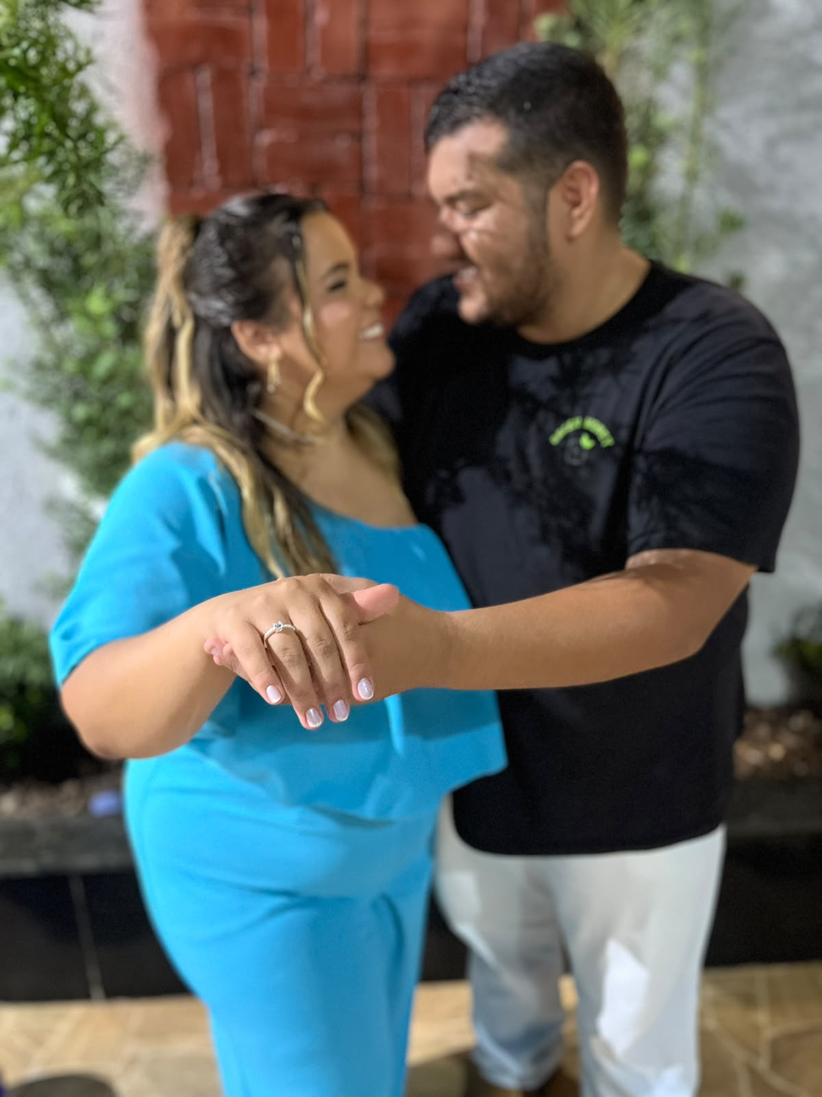 Thayssa e Gabriel aos risos, com as mãos entrelaçadas e a aliança de noivado em destaque